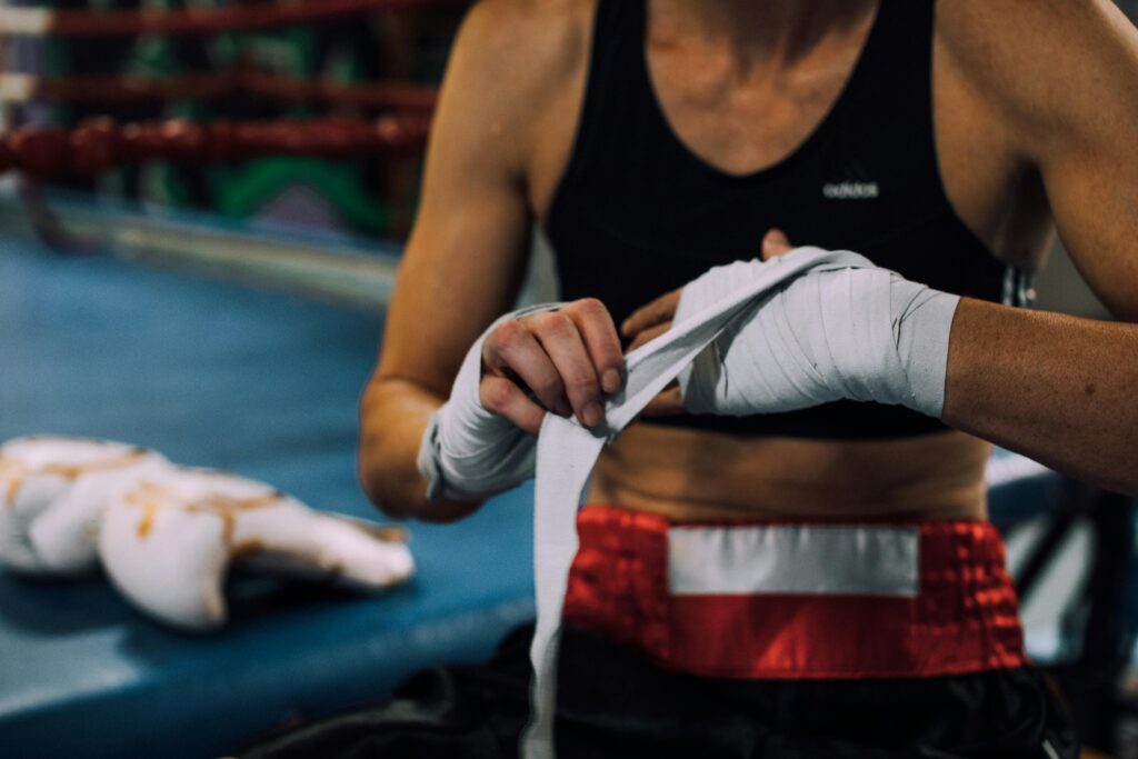 A female boxer prepares for a training session by wrapping her hands in a boxing gym.